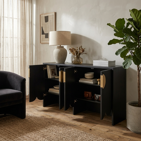 Modern living room with a black sideboard, lamp, books, and a plant.