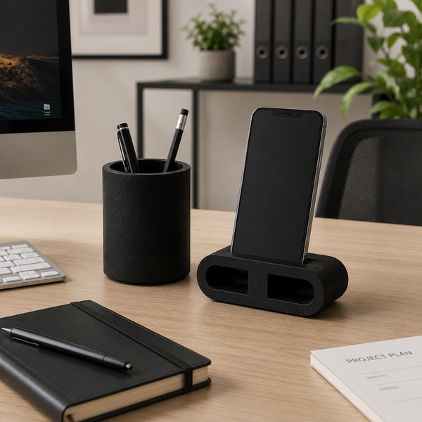 Desk setup with phone stand, pen holder, notebook, and smartphone on a wooden desk.
