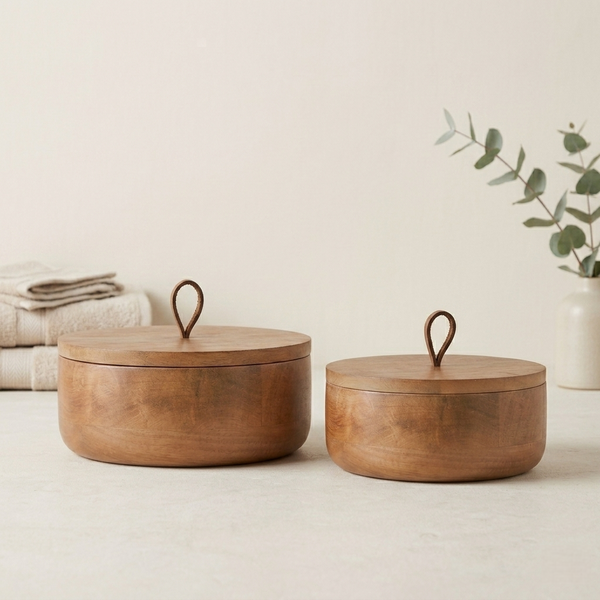 Two wooden storage boxes with lids on a light surface with a plant in the background