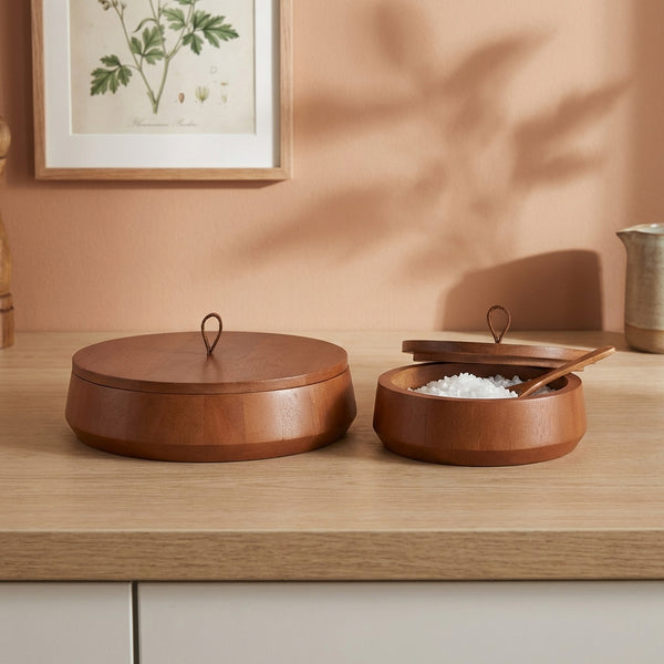 Wooden containers on a wooden surface with a framed plant picture in the background.