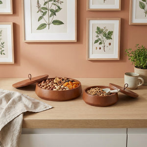 Bowl of snacks on a wooden surface with framed botanical prints on the wall.