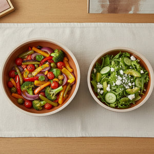 Two bowls of salad on a light-colored tablecloth.