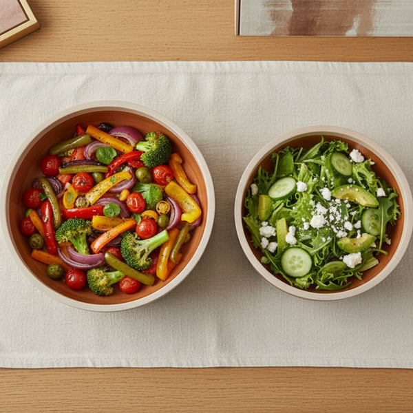 Two bowls of salad on a light-colored tablecloth.