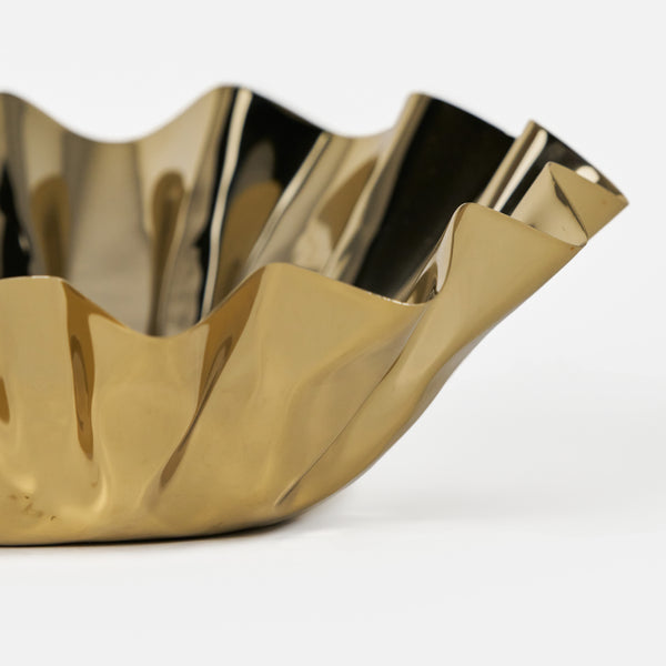 Gold decorative bowl with wavy design on a white background