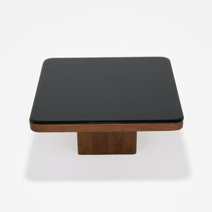 Square table with black top and wooden base on a white background
