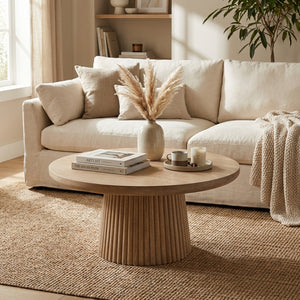 Beige sofa with a round wooden coffee table in a living room setting.