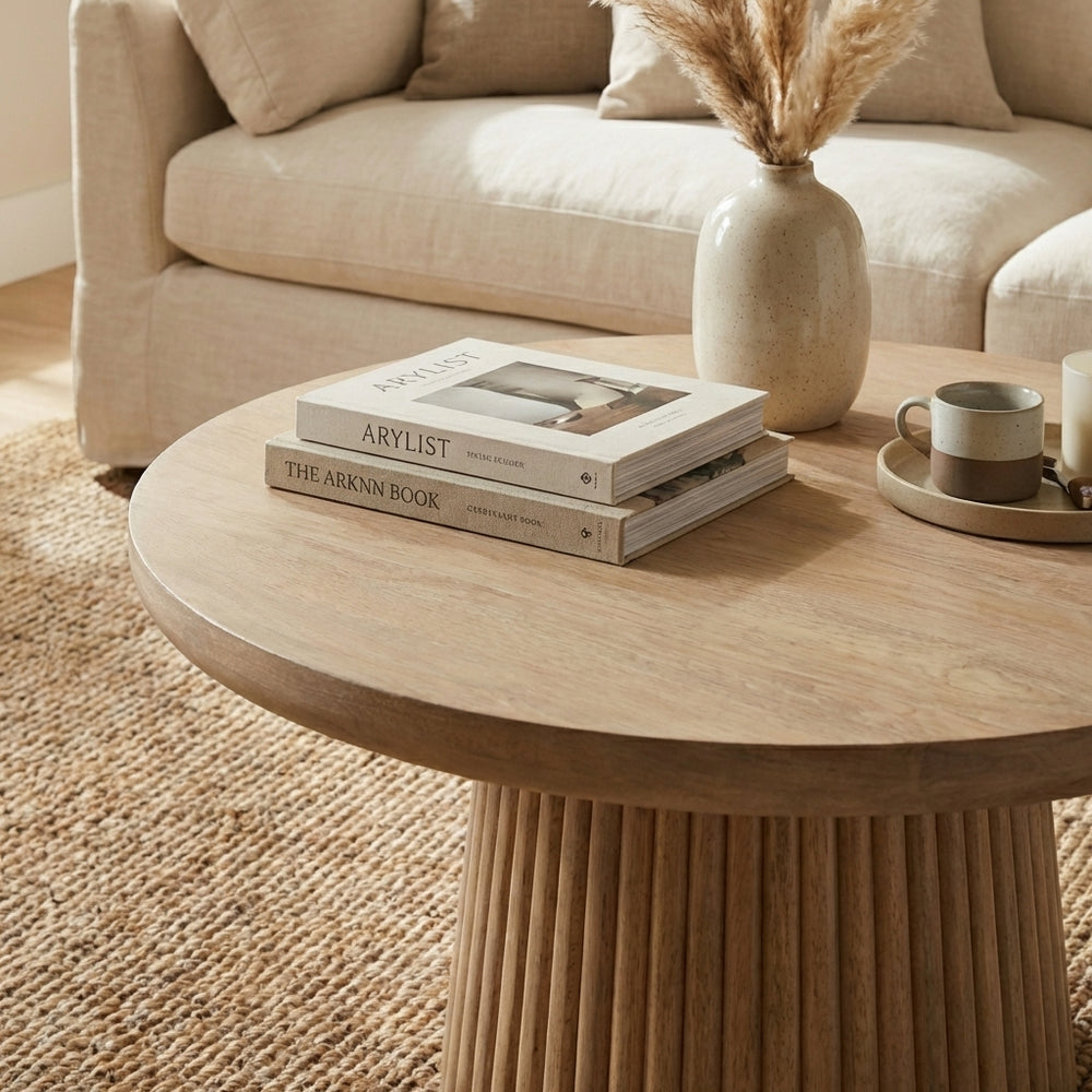 Beige sofa with a round wooden coffee table in a living room setting.