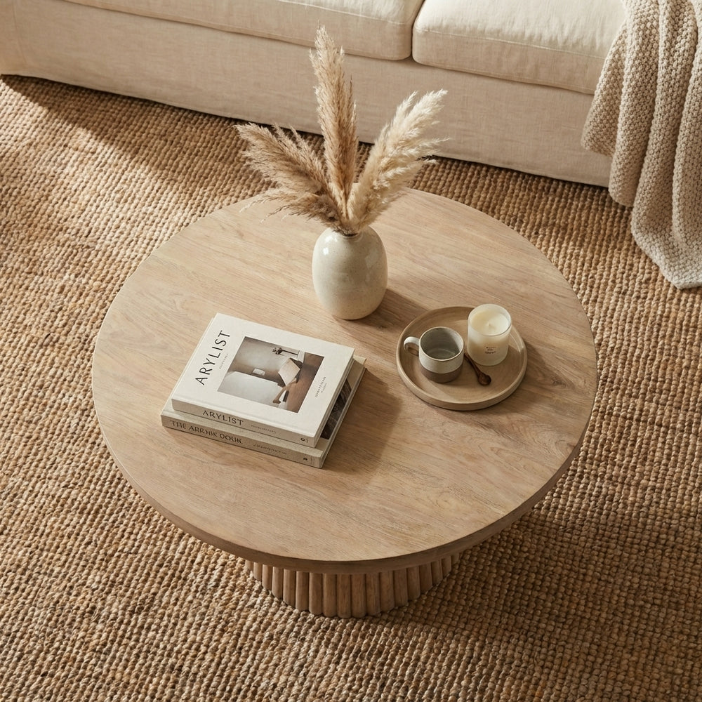 Beige sofa with a round wooden coffee table in a living room setting.