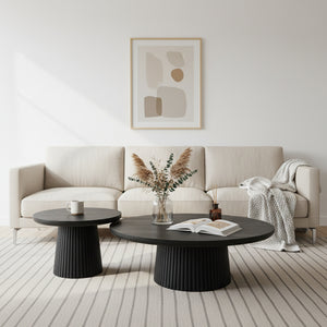 Modern living room with a beige sofa, black coffee table, and abstract art on the wall.