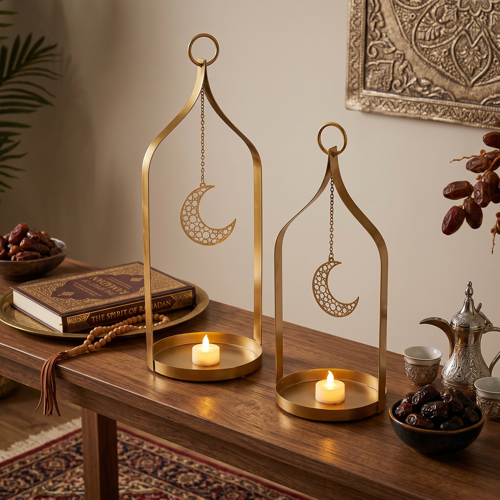 Two gold lanterns with moon designs on a wooden table with candles and books.