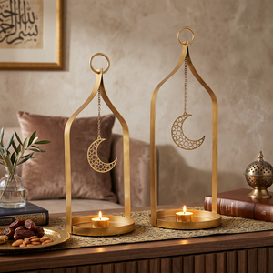 Two gold lanterns with moon designs on a table with candles and books.