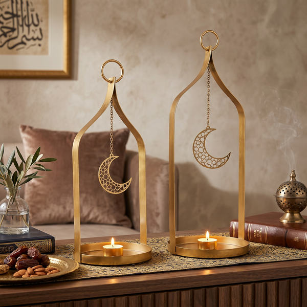 Two gold lanterns with moon designs on a table with candles and books.