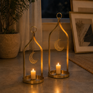 Two gold lanterns with moon designs holding candles on a surface.